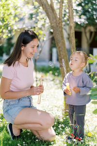 Side view of mother and daughter sitting at park