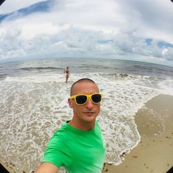 Portrait of man wearing sunglasses at beach against sky