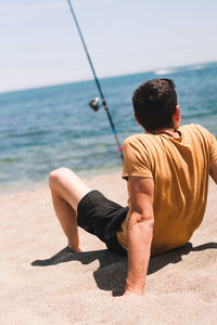 Rear view of man sitting on beach