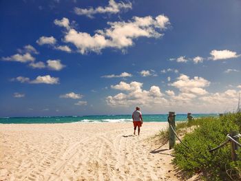 Rear view of woman on beach against sky