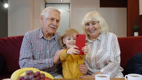 Grandparent with granddaughter using mobile phone at home