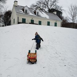 Low angle view of built structures child pulling a sled in snow