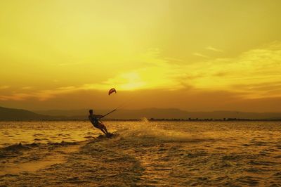 Silhouette man surfing in sea against sky during sunset