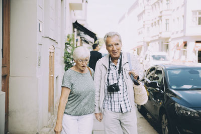 Senior couple walking on sidewalk in city during vacation