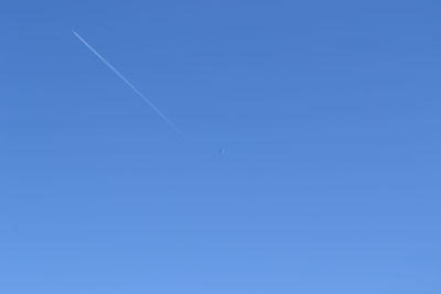 Low angle view of vapor trail against clear blue sky