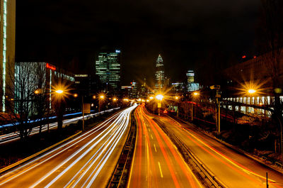 Light trails on road amidst buildings in city at night