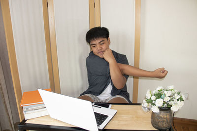 Young woman using mobile phone while sitting on table