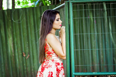 Side view of woman standing by fence