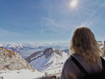 Rear view of woman on snowcapped mountain against sky