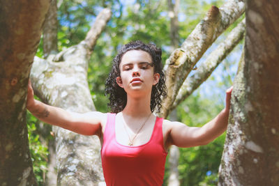 Teenage girl standing by tree trunk at park