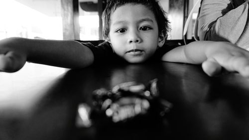 Close-up portrait of cute boy playing on table at home