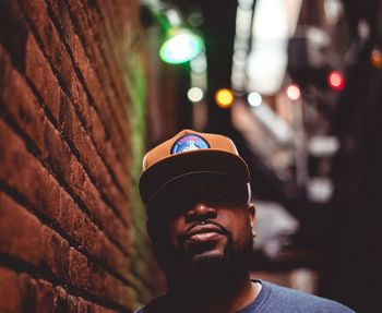 Portrait of man wearing cap against illuminated city at night