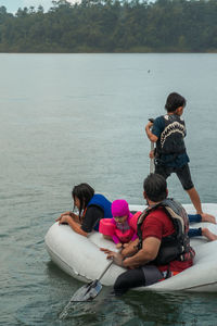 Rear view of people sitting on boat in lake