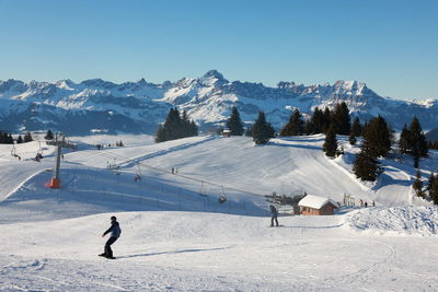 People skiing on snow covered landscape