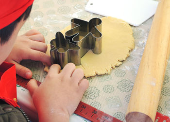 Cropped hands of boy making cookies on table at home