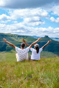 Rear view of woman standing on grassy field against sky