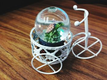 Close-up of snow globe in toy bicycle on wooden table