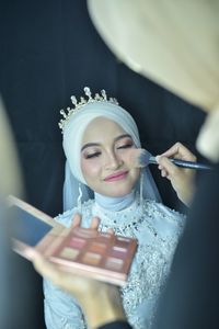 Midsection of beautician applying make-up on bride