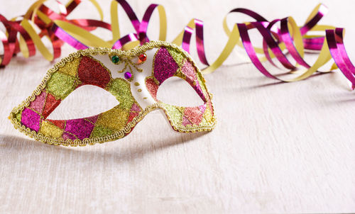 Close-up of venetian mask by ribbon on table