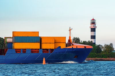 Lighthouse by sea against clear sky