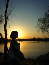 Silhouette of woman standing on tree trunk