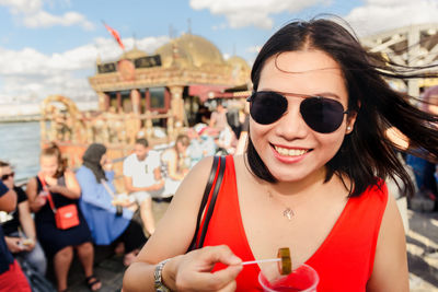 Portrait of woman wearing sunglasses holding pickle while outdoors