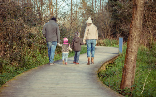 Rear view of men walking on footpath amidst trees