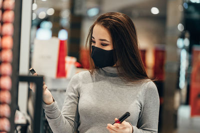 Woman holding smart phone while standing on laptop