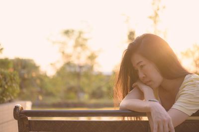 Portrait of young woman sitting on railing