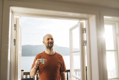 Smiling man holding mug with coffee
