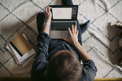 Directly above shot of businessman working on laptop at home