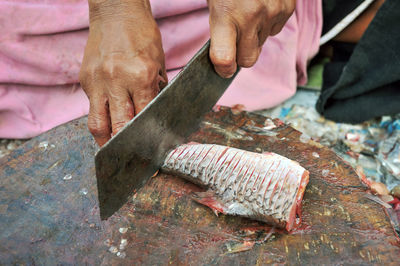 Cropped hands of woman cutting fish at market