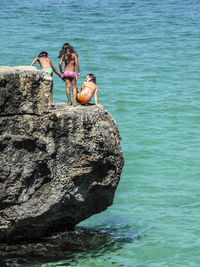 Woman sitting on rock by sea