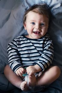 Portrait of cute baby boy lying down on bed at home