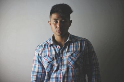 Portrait of young man standing against white background