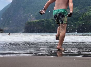 Low section of boy running at beach