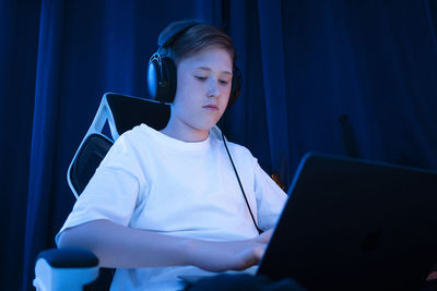 Boy with headphones using laptop at home