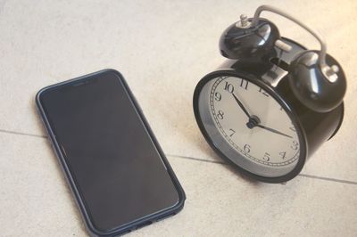 Close-up of alarm clock and mobile phone on the table