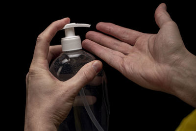 Close-up of man holding hands over black background