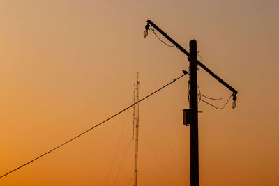 Low angle view of silhouette electricity pylon against sky during sunset