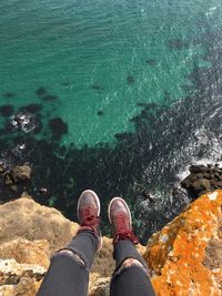 Low section of person standing on rock by sea