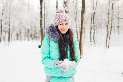 Portrait of smiling young woman standing on snow covered field