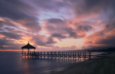 Pier over sea against sky during sunset