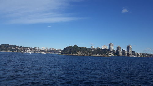 Sea by buildings against blue sky