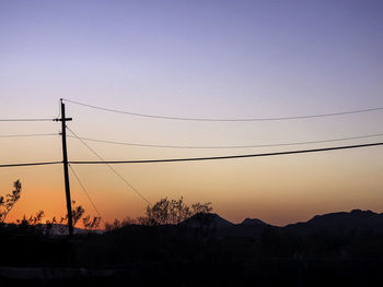 Silhouette electricity pylon against sky during sunset