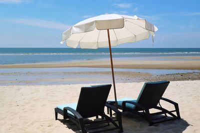 Bed beach and white umbrella on tropical beach with blue sky in the summer morning.