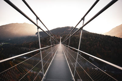 Long empty footbridge against clear sky during sunrise