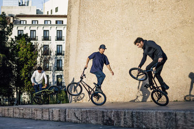 Three men practicing tricks with the bmx bike in the city