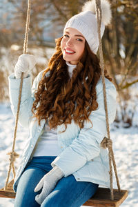 Portrait of young woman sitting on swing at playground