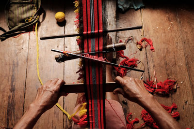 Overhead view of woman weaving red striped fabric